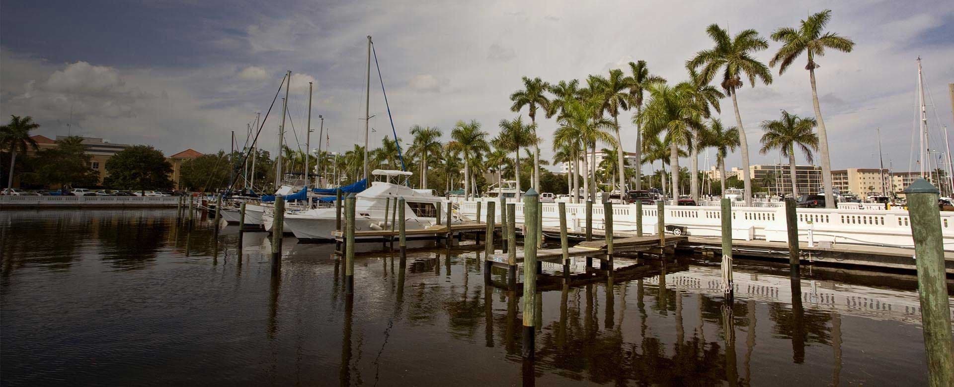 A marina scene featuring several boats docked in calm water under a clear blue sky.